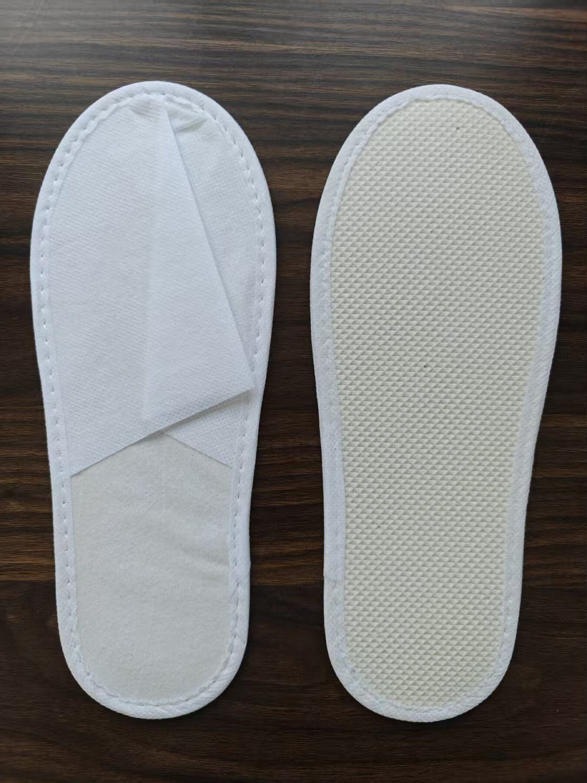 White non-woven hospitality guest slipper shown from the upper and sole
