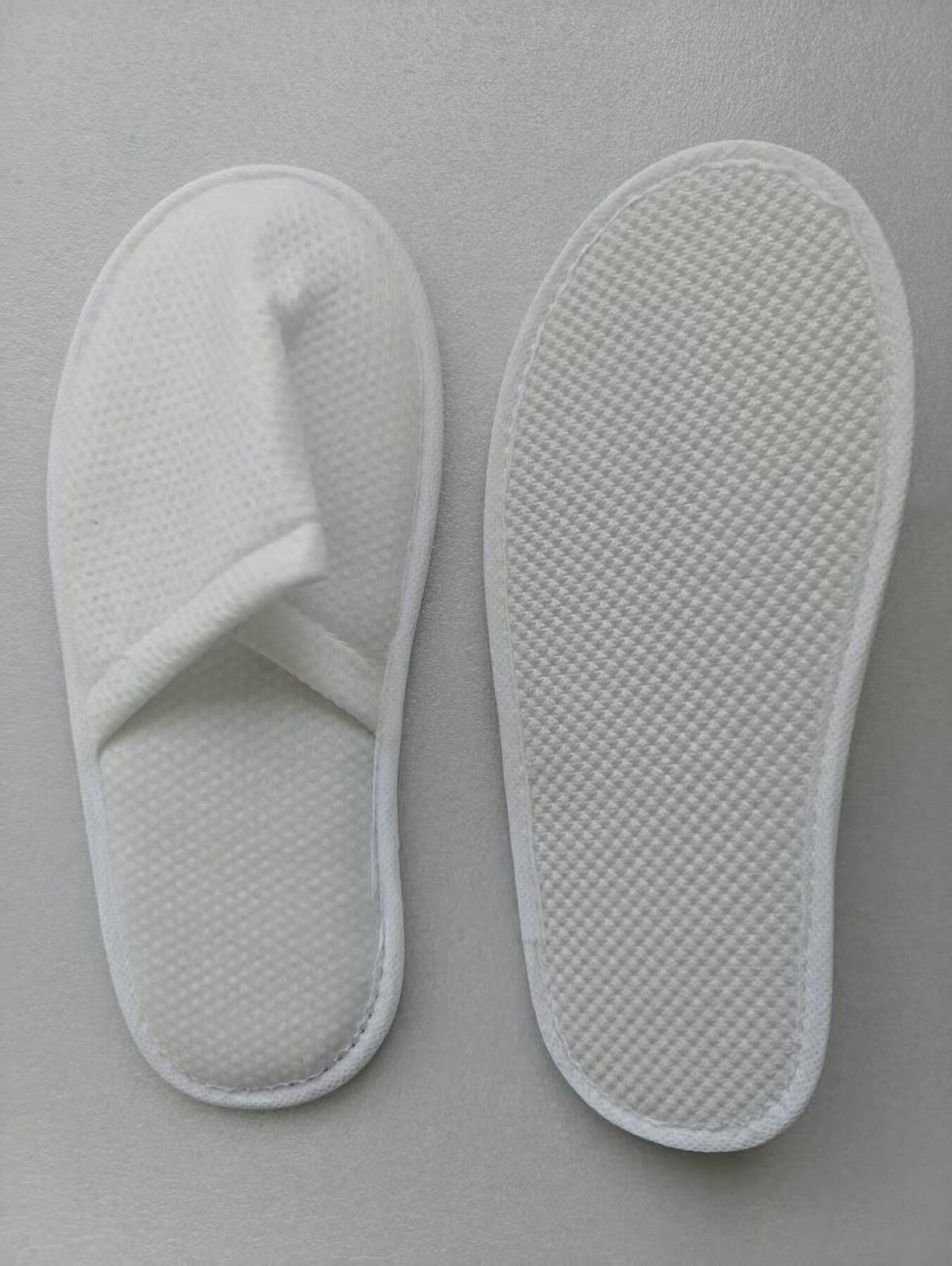 White pearl-cotton hospitality guest slipper shown from the upper and sole